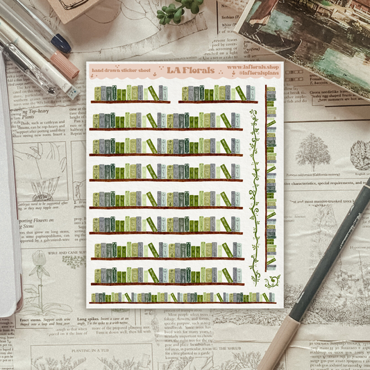 A sticker sheet showing a pattern of bookshelves sits on a vintage newspaper surface with stationery items.

