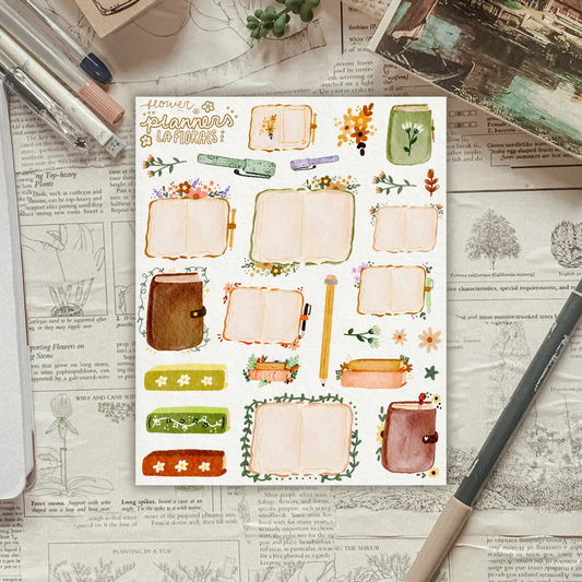 Textured background with a sticker sheet of flowers and open planners laying on top. 
